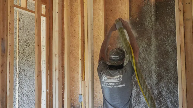 An Advanced Thermal Concepts technician directing an insulation hose into a wall cavity.